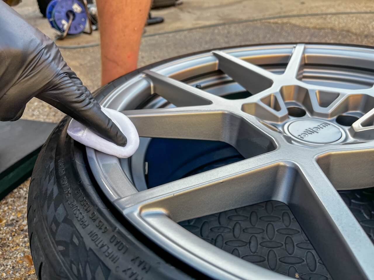 White pad with ceramic coating being applied to gray alloy wheel