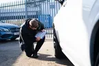 Technician inspecting a lease car wheel and recording its condition