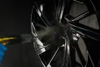 Powder coating being sprayed onto a black alloy wheel