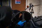 Technician straightening a buckled alloy wheel on a repair machine