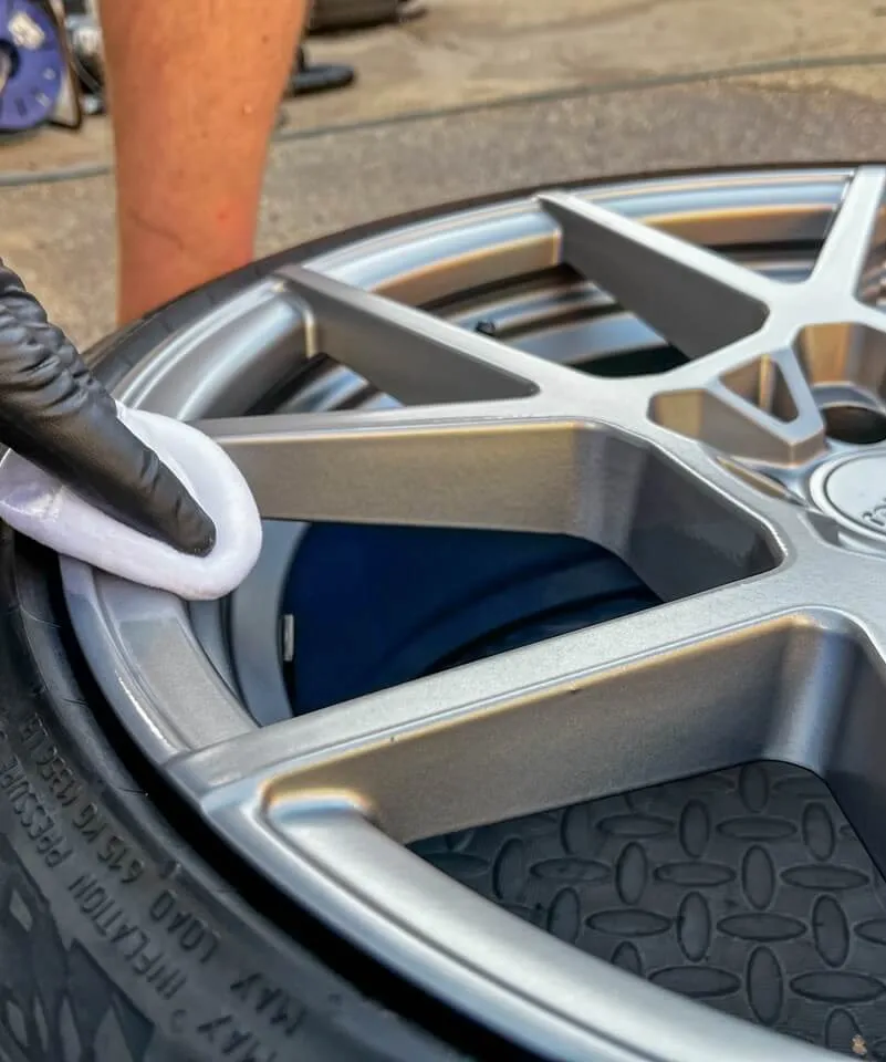 White pad with ceramic coating being applied to grey alloy wheel