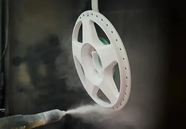 Split rim alloy in the spray booth being powder coated in white