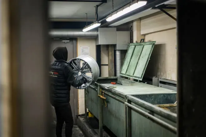 Rolling Rims employee carrying an alloy wheel to the chemical stripping bath