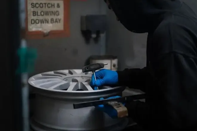 A stripped alloy wheel that is being attached to the mounting system ready for powder coating