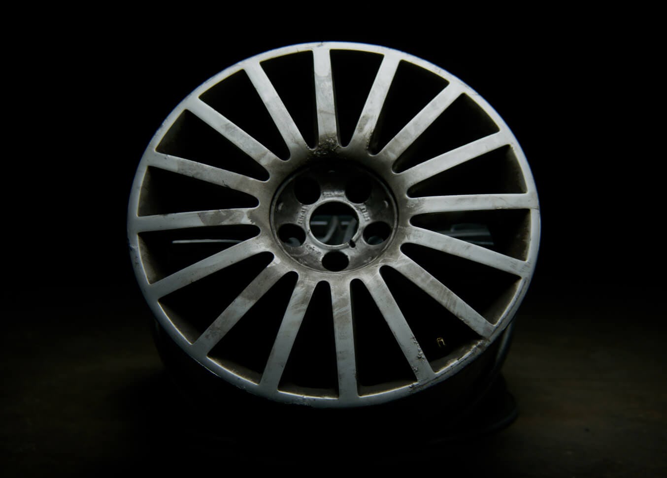 Damaged silver alloy wheel with the powder coating flaking
