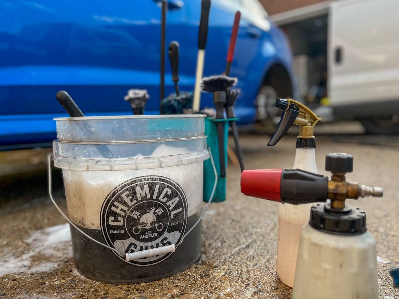 chemical guys bucket full of a mix of water and cleaning solution and a snow foam lance ready to clean alloy wheels