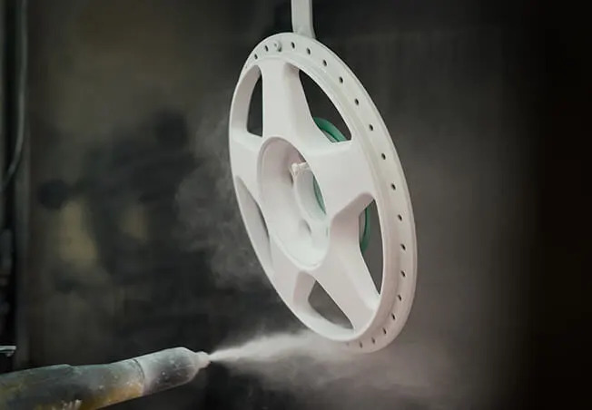 Split rim alloy in the spray booth being powder coated in white