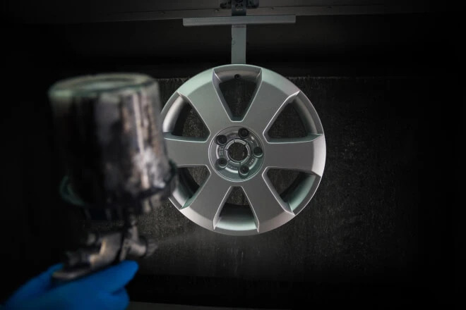 Alloy wheel hanging in the spray booth being painted silver