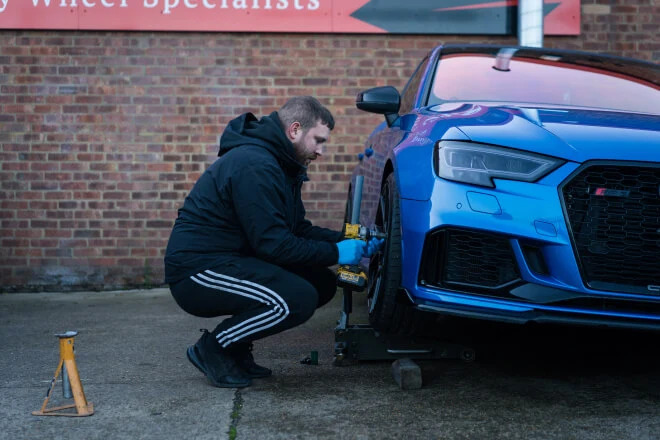 Rolling Rims employee removing a wheel from an Audi ready to take into the workshop
