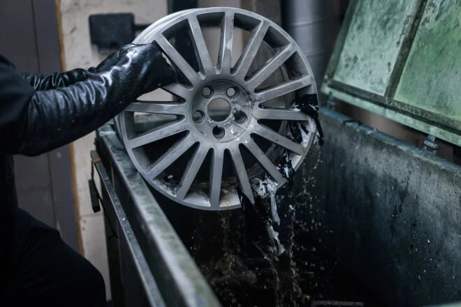 Alloy wheel that has been taken out of the chemical stripping bath and has the old paint falling off
