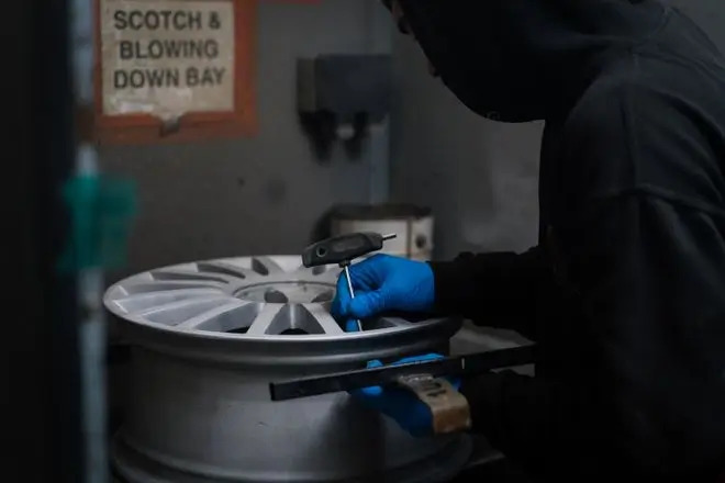 A stripped alloy wheel that is being attached to the mounting system ready for powder coating