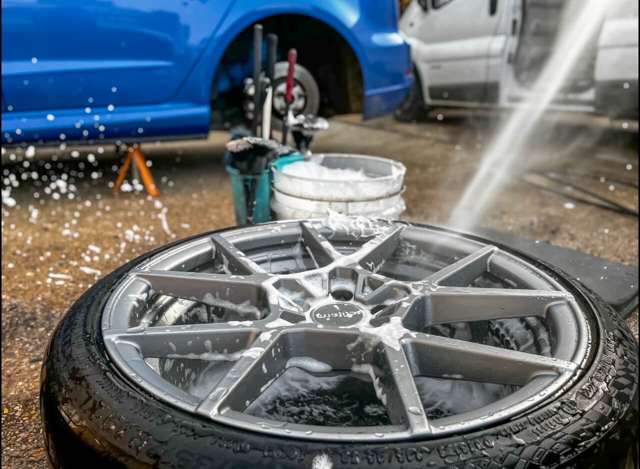 Gray alloy wheel with soap being jet washed clean at Rolling Rims